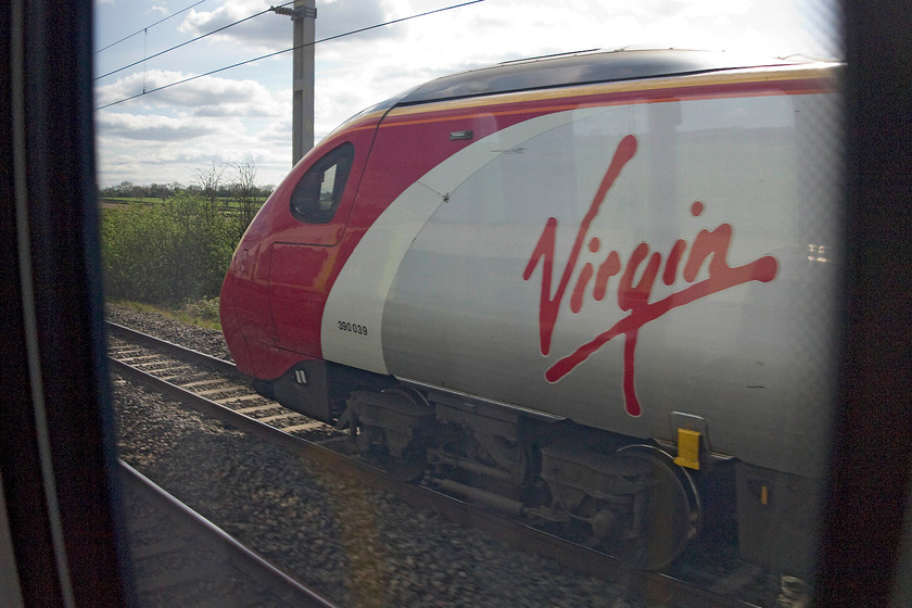 390039, VT 15.00 London Euston-Carlisle (1S78, RT) from 350104, LM 14.47 London Euston-Birmingham New Street, near Cheddington 
 On the four track section of the WCML it is quite common for one train to pass another when both are travelling in the same direction. It creates a strange sensation of slow motion and a chance to wave to fellow passengers! I have captured such a scene here near Cheddington just south of Leighton Buzzard. 390039, forming the 15.00 Euston to Carlisle, slowly overhauls 350104 on which we were travelling working the 14.47 Euston to Birmingham New Street. 
 Keywords: 390039 1S78 Cheddington