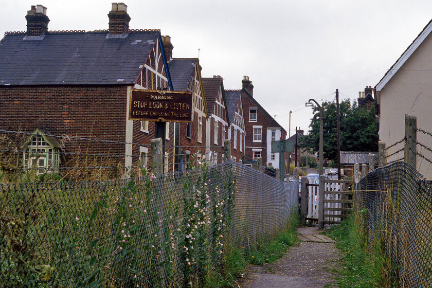 Former GWR trackbed & crossing, Bemerton 
 A view taken with my back to foot crossing over the remaining two tracks of the once quadrupled route to the north of Salisbury. The area in the foreground was once occupied by the GWR independent lines that diverged from the L&NWR tracks at Wilton. This path is still in use today leading from Gramshaw Road over the railway to Lower Road. Notice the cast sign to the left possibly of GWR heritage warning pedestrians to stop, look and listen before crossing the tracks that have now been removed, in this case, some eight years previously. 
 Keywords: Former GWR trackbed crossing Bemerton Gramshaw Road