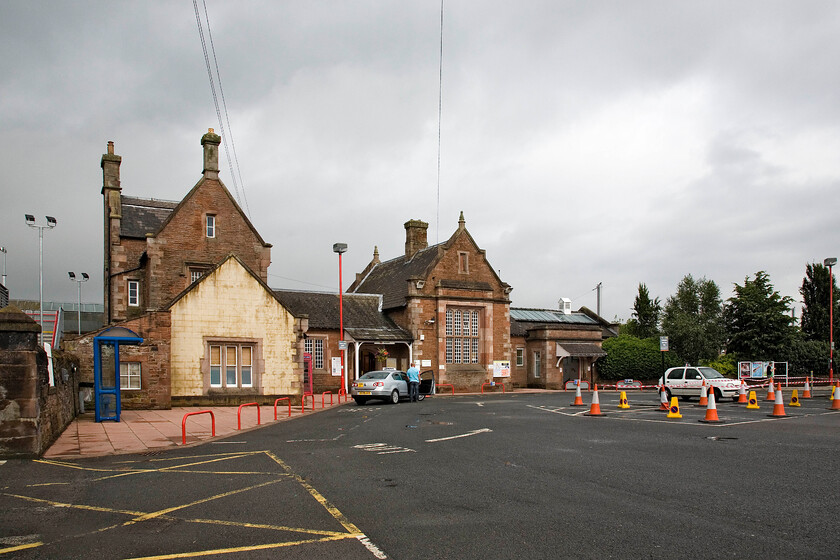 Frontage, Penrith station 
 Penrith station was built by the Lancaster and Carlisle Railway and opened in 1846. It was designed by renowned architect Sir William Tite and today is Grade II listed. On the day of our visit, the car park was being extended and re-surfaced. Andy has parked his trusty Micra in the car park and is attending a nearby food van to purchase his much-needed breakfast bacon roll! 
 Keywords: Frontage Penrith station