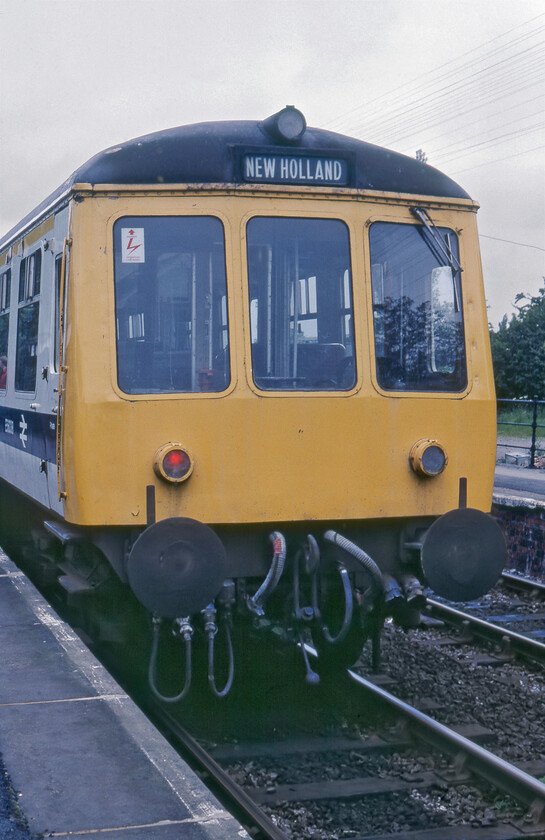 Class 114 DMU, 12.00 Cleethorpes-New Holland Pier, Goxhill Station station 
 A programme to refurbish the entire Class 117 Derby-built first-generation DMUs commenced in late 1977 and was completed by 1983. The work was carried out by BREL at Doncaster with the units being released in a somewhat curious white body colour with a large blue stripe. However, this extensive refurbishment programme did result in the units staying in service until 1992 being some of the last first-generation units in use. Looking smart in its new livery and wearing the South Yorkshire PTE logo on the side of the DTC the 12.00 Cleethorpes to New Holland Pier pauses at Goxhill station. 
 Keywords: Class 114 DMU 12.00 Cleethorpes-New Holland Pier Goxhill Station station