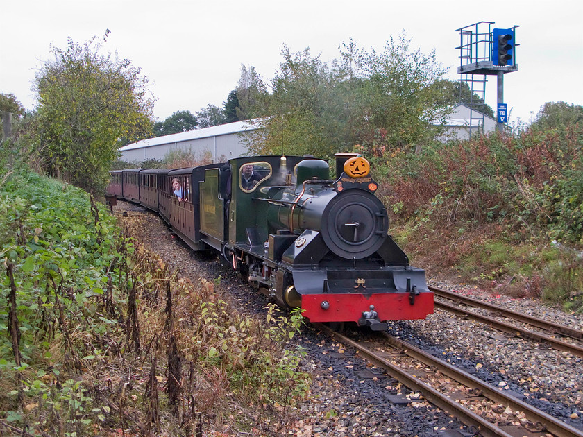 7, 14.20 Aylsham-Wroxham, Wroxham station 
 The 14.20 Aylesham to Wroxham Bure Valley Railway service arrives at its destination with number 7 'Spitfire' leading the train. Notice the large colour light rising above the embankment to the right, this is located on the Norwich to Sheringham Network Rail line. 
 Keywords: 7 14.20 Aylsham-Wroxham Wroxham station Bure Valley Railway Spitfire