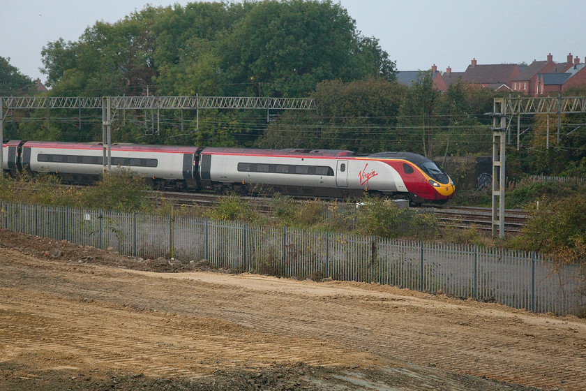 Class 390, VT 07.23 London Euston-Birmingham New Street (9G05), site of Roade station 
 A class 390 passes through Roade past the site of the old station working the 07.23 Euston to Birmingham New Street. Notice the new houses in the background, the same will soon appear on the flattened land in the foreground as the village of Roade continues to grow at an alarming rate. 
 Keywords: Class 390 07.23 London Euston-Birmingham New Street 9G05 site of Roade station