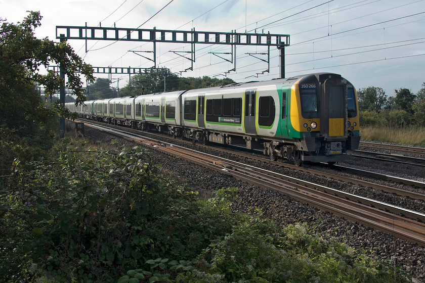 350266, 350267 & 350247, LN 07.21 London Euston-Liverpool Lime Street (9F38, 8L), Ashton Road bridge 
 A trio of class 350s approaches Roade between Northampton and Milton Keynes. 350266, 350267 and 350247 are working the 07.21 Euston to Liverpool Lime Street. Since the May timetable changes, passengers from Northampton, and a number of other stations can enjoy direct trains to and from Liverpool. However, the journey follows a slow stopper pattern so it takes an awfully long time to get there. For us in this area, it is still quicker to go south to Milton Keynes and catch a Virgin Pendolino north. I have yet to check out the price difference though! 
 Keywords: 350266 350267 350247 07.21 London Euston-Liverpool Lime Street 9F38 Ashton Road bridge