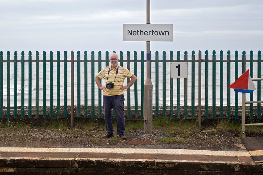 Andy, Nethertown station 
 This is our second visit to this station, see.... https://www.ontheupfast.com/p/21936chg/30061915056/x22-andy-nethertown-station Andy proudly models on Nethertown station with the Irish Sea in the background. The station once boasted a station building, some sidings and a signal box seeing its heyday during World War II bringing many members of the military to and from a large training camp constructed nearby. After the war, the same camp was the home to thousands of construction workers involved with the building of the Sellafield plant (then known as Calder Hall). Today, it has a very meagre stopping service with passenger numbers being just 960 during 2022 and 2023 equating to just 2.6 people per day. 
 Keywords: Andy, Nethertown station