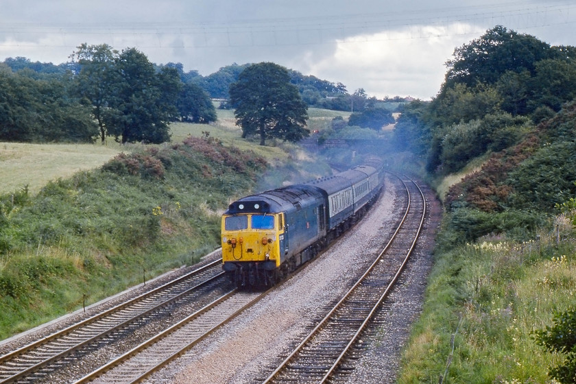 50023, 10.30 London Paddington-Penzance, Whiteball 
 Having surmounted Whitaball summit and exited the tunnel that is just out of sight around the corner, 50023 'Howe' opens up and gets the 10.30 Paddington to Penzance up to speed again and onwards towards Exeter. A couple of nights previously I camped wild in a field behind the trees to the right. Despite being withdrawn in 1990, it lingered on as a source of spares until being cut-up at Barrow Hill in 2004. 
 Keywords: 50023 10.30 London Paddington-Penzance Whiteball