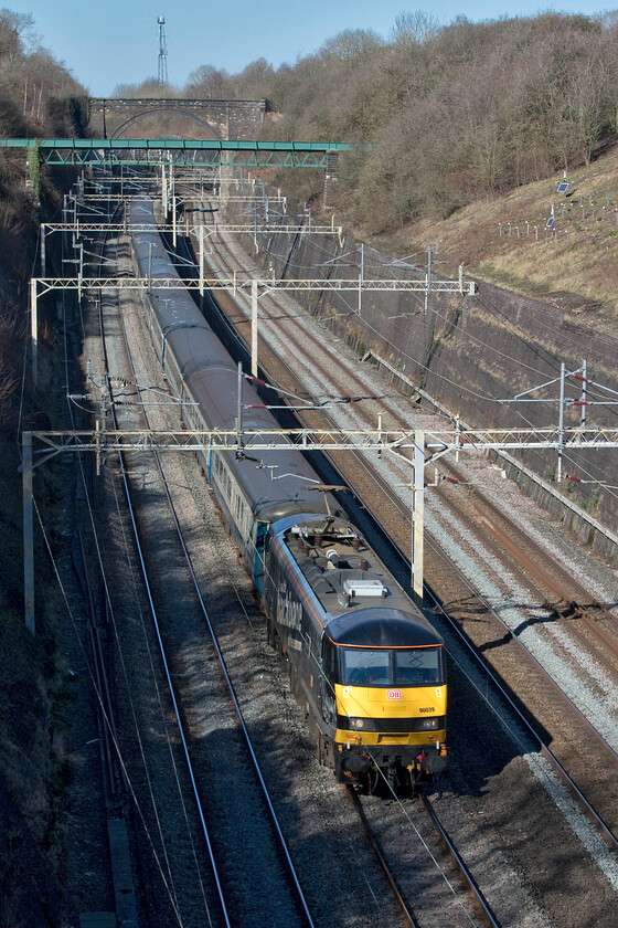 90039, 11.01 Liverpool South Parkway-Wembley Central footex (1Z22, 11E), Roade cutting 
 Former Grand Central prepared 90039 'The Chartered Institute of Logistics and Transport' sweeps through Roade cutting leading a set of former BR Mk.II stock. The footex was carrying Liverpool fans from Liverpool South Parkway to Wembley for the EFL final, a match that the Merseyside team won beating Chelsea 11-10 after penalties. The huge wording adorning the side of 90039 reads 'I am the backbone of the economy' in a further nod to the actual name of the locomotive. 
 Keywords: 90039 11.01 Liverpool South Parkway-Wembley Central footex 1Z22 Roade cutting The Chartered Institute of Logistics and Transport