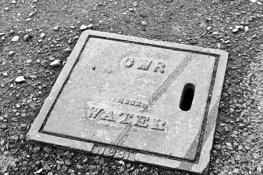 Water main cover, former Trowbridge goods shed 
 The GWR put their name on everything! This included covers for access to water pipes as seen here in the former Trowbridge goods yard that was being used as a car park when this photograph was taken. Notice my bicycle tyre marks running across the cover! 
 Keywords: Water main cover former Trowbridge goods shed