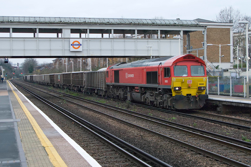 59203, 12.34 Acton TC-Crawley (7069), Kensington Olympia station 
 Looking for all intents and purposes like a Class 66 59203 brings the 12.34 Acton to Crawley loaded stone train through Kensington Olympia station. 59203 was one of a second batch of the class that arrived on the UK shores during the summer of 1995. The first batch of the class, that arrived some ten years prior to this, really broke the mould of UK locomotive design and production being entirely produced from beginning to end in North America and were a clear sign of things to come. 
 Keywords: 59203 12.34 Acton TC-Crawley 7069 Kensington Olympia station stone train