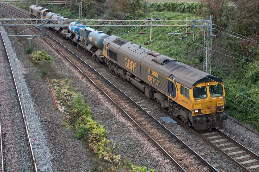 66707 & 66724, 11.00 Kings Norton-Kings Norton (3J01, 7L), Victoria bridge 
 Wearing its characteristic brown filth indicating that it has been undertaking railhead treatment work, 66707 'Sir Sam Fay-Great Central Railway' leads the 11.00 Kings Norton to Kings Norton via the rest of Midlands RHHT working! With 66724 'Drax Power Station' on the rear, the jets were not in operation during this part of its journey meaning either the crew deemed that the busy WCML up slow line was free from leaf drop debris or that the tanks were out of water. The train is seen passing Victoria bridge just south of Roade. 
 Keywords: 66707 66724 11.00 Kings Norton-Kings Norton 3J01 Victoria bridge Sir Sam Fay-Great Central Railway Drax Power Station