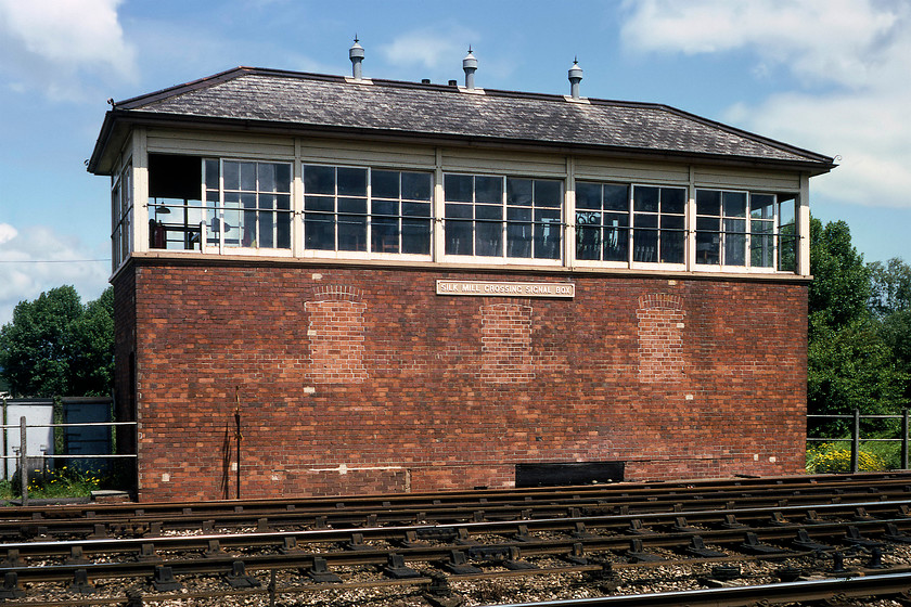 Silk Mill Crossing signal box (GW, 1940) 
 Built in 1940 during wartime expansion of Fairwater Yard, Silk Mill Crossing signal box is seen in some welcome summer sunshine. It is a 'new' Type 12b box with a hipped roof and two thirds two over two glazed windows. It closed on 21.03.87 when Exeter panel took over control of all the signalling in the Taunton area. Whilst the box still has its cast plate the locking room windows have been bricked up that was common practice to improve the working environment for the signalman, helping guard against cold winter drafts. While I was here, the shift change took place and Smithy came on duty who I spent some time with last year in Cogload box, see...... https://www.ontheupfast.com/p/21936chg/26681567604/smithy-cogload-signal-box 
 Keywords: Silk Mill Crossing signal box