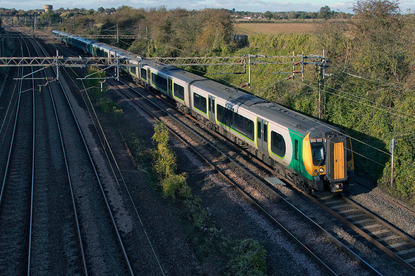 350103 & 350372, LN 13.14 Birmingham New Street-London Euston (1W62, 1L), Victoria bridge 
 The autumn sun illuminates the side of 350103 and 350372 as it passes Victoria bridge just south of Roade forming the 13.14 Birmingham New Street to Euston. Notice the concrete water tower on the skyline to the top left of the image. In recent months, this has begun a much-awaited conversion into a domestic property, one that has caught the attention of Grand Design's Kevin McCloud who has made a number of visits to observe the work taking place. 
 Keywords: 350103 350372 13.14 Birmingham New Street-London Euston 1W62 Victoria bridge