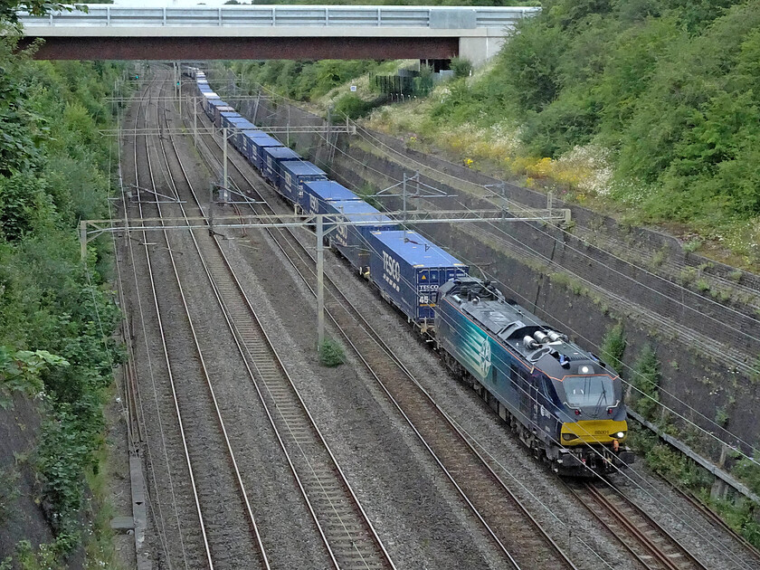 88001, 13.37 DIRFT-Tilbury (4L48, RT), Roade cutting 
 In the last week or so DRS has once again moved the daily 4L48 Daventry to Tilbury Tesco Express back to electric haulage. 88001 'Revolution' is seen leading the train through Roade cutting almost catching me out by the speed it was travelling taking much less time to get here from Northampton such is the power of these locomotives. 
 Keywords: 88001 13.37 DIRFT-Tilbury 4L48 Roade cutting Revolution