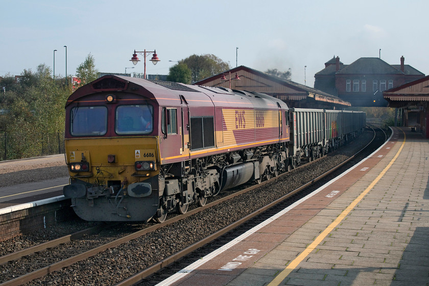 66116, 10.28 Banbury Reservoir Tarmac-Mountsorrel (4M31), Tyseley station 
 66116 has just been checked behind a service train and is getting up to speed again with the 4M31 10.28 Banbury Tarmac to Mountsorrel empty stone train. The driver had just given Andy and myself a cheery toot on the horn and close examination of the cab reveals him giving us an equally cheery wave as we stand on the platform end at Tyseley station. Incredibly, EWS was sold to Deutsche Bahn ten year's ago and yet, 66116 is still in the companies distinctive livery and carries its full branding including the three beasties logo on the flank of the rear cab. 
 Keywords: 66116 10.28 Banbury Reservoir Tarmac-Mountsorrel 4M31 Tyseley station