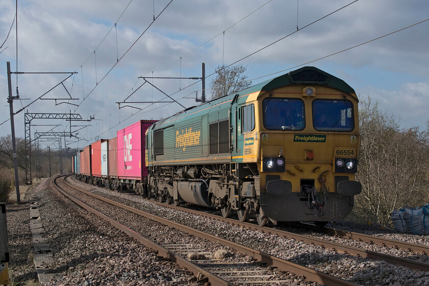 66554,12.16 Lawley Street-London Gateway (4L46, 1E), Bugbrooke footbridge 
 66554 leads a long and well-loaded 4L46 12.16 Lawley Street to London Gateway service past Bugbrooke in Northamptonshire. This freight, along with all others, is usually kept well away from this route normally being sent via Northampton. However, due to a week-long closure of Crick tunnel it is taking the Weedon route being pathed in between the Avanti West Coast and London Northwestern services no doubt causing frustration to their drivers! 
 Keywords: 66554 12.16 Lawley Street-London Gateway 4L46 Bugbrooke footbridge Freightliner