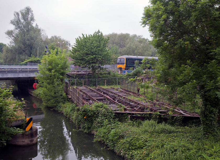 165107, GW 11.18 Oxford-Oxford Up Carriage Sidings ECS (5L24) & Rewley Road swingbridge 
 165107 has run round and is returning to Oxford station as the 5L24 ECS ready to work back to Didcot Parkway. In the foreground is Rewley Road swing bridge, a well known feature here next to the Sheepwash Channel, a tributary to the Oxford Canal. Robert Stephenson designed and constructed the swing bridge in 1850. It was re-built again twice, lastly when steel girders were included. The bridge is now a scheduled structure and there have been numerous, but so-far unsuccessful, bids to restore it. 
 Keywords: 165107 ECS 5L24 Rewley Road swingbridge