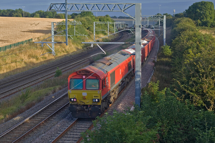 66097, 02.00 Peak Forest-Limbury Road (6C76, 17L), Irchester SP927667 
 For once, the weather gods are looking down on me! A fairly wide hole in the otherwise cloud-covered sky is shining down and illuminating 66097 as it approaches Irchester just south of Wellingborough. The DB Class 66 is leading the 6C76 02.00 Peak Forest to Limbury Road loaded stone train. This is the second time that I have photographed this train in the last few weeks, see ....https://www.ontheupfast.com/p/21936chg/30057285306/x700018-05-14-three-bridges-bedford 
 Keywords: 66097 02.00 Peak Forest-Limbury Road 6C76 Irchester SP927667