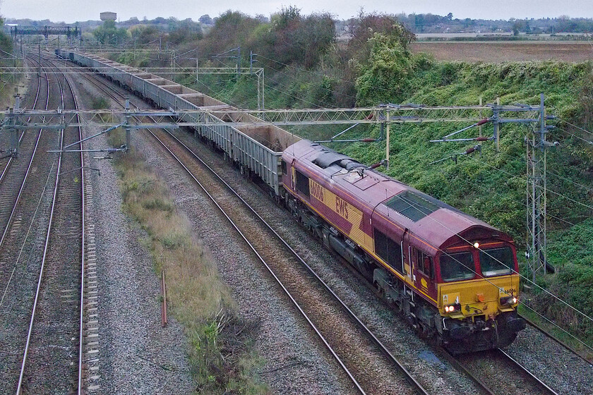 66006, 11.59 Burton-ot-Wetmore-Acton TC (6V96, 11L), Victoria bridge 
 With the number of Class 66s still remaining in their as-built EWS liveries complete with branding now getting far fewer as DB Cargo continues to repaint and rebrand them catching one is getting more tricky. In fact, 66006 leading the Burton-ot-Wetmore to Acton TC empty wagons past Victoria bridge near Roade is the earliest member of the class still wearing this livery. The paintwork is standing up pretty well considering that it dates from October 1998. Could you imagine a first-generation diesel still wearing its original BR paintwork twenty-six years after it entered service? Having said this, not many actually survived that long in service! With the light all but gone it really ought to be time to head for home but with just one more thing of interest approaching, not quite yet....! 
 Keywords: 66006 11.59 Burton-ot-Wetmore-Acton TC 6V96 Victoria bridge EWS