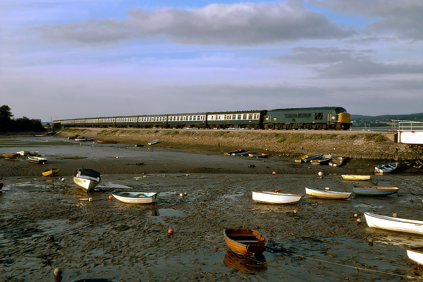 46023, 12.05 Leeds-Penzance (1V86), Cockwood Harbour 
 On driving past Cockwood Harbour on the way home the sun was absolutely perfect so I perswaded Graham to stop for a while and take advantage of the superb lighting. 46023 heads west with the 12.05 Leeds to Penzance service formed of a uniform set of Mk. 1 stock. 46023 would continue in service for another three years eventually being cut up at Basford Hall in the spring of 1994. Interestingly, the small boat leaning at an angle on the harbour's mud appears to have lost its For Sale board that was seen yesterday; perhaps the owner sold it, see.... https://www.ontheupfast.com/p/21936chg/29740304004/x50042-13-30-paddington-paignton 
 Keywords: 46023 12.05 Leeds-Penzance 1V86 Cockwood Harbour Peak