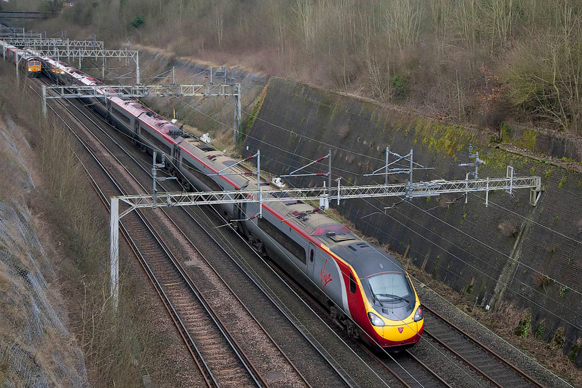 Class 390, VT 10.00 Glasgow Central-London Euston (9M53) & 66729, 10.46 Felixstowe North-Hams Hall FLT (4M23), Roade Cutting 
 An unidentified class 390 heads south through Roade Cutting forming the 10.00 Glasgow Central to London Euston, a journey that it will complete in about 35 minutes time. Notice, 66729 just entering the frame on the left leading the 10.46 Felixstowe North to Hams Hall Freightliner. 
 Keywords: Class 390 9M53 66729 10.46 Felixstowe North-Hams Hall FLT 4M23 Freightliner Roade Cutting