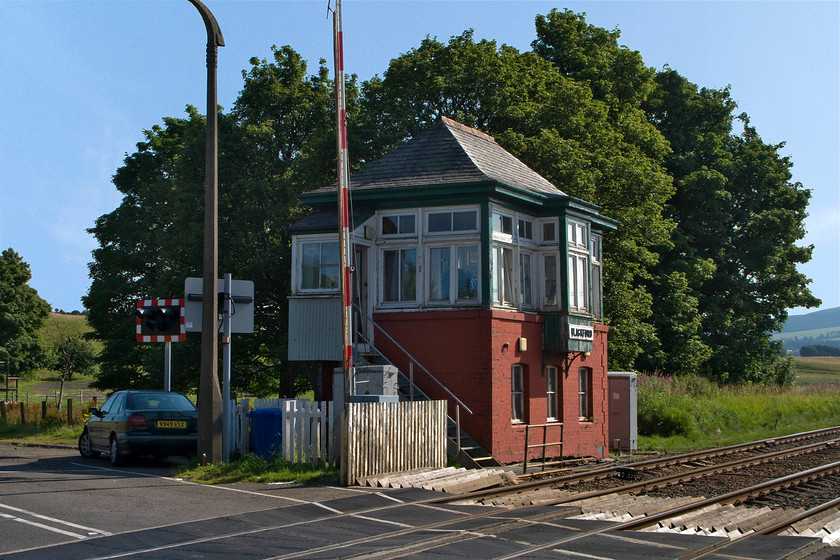 Blackford signal box (LMS, 1933) 
 I really like the design of the LMS' Scottish division boxes with their sprocketed hipped roofs and central observation windows, they appear both architecturally balanced, attractive and sturdy. Unlike Longforgan box https://www.ontheupfast.com/p/21936chg/28963896804/longforgan-signal-box-lms seen earlier in the day, Blackford retains its frame room windows that appear to be the original frames. The box is at a remote location at the level crossing to the north of the village where the old A9 main road used to cross the line now replaced by a dual carriageway that bypasses the village opened in 1978. 
 Keywords: Blackford signal box LMS