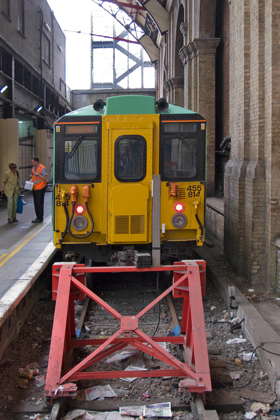 455814, SN 12.23 London Victoria-Epson Downs (2R52), London Victoria station 
 The Class 455s must rank amongst the ugliest and most utilitarian designs to come off the BREL drawing boards in the early 1980s. In its latest incarnation carrying a Southern livery 455814 stands at Victoria waiting to leave with the 12.23 to Epson Downs. Notice the rubbish laying about on the trackbed by the buffers. It really would not take much to get a cleaning team down during the quieter hours late at night with the third rail switched off and for them to do a quick sweep but I suppose the H & S brigade would preclude this from taking place. 
 Keywords: 455814 12.23 London Victoria-Epson Downs 2R52 London Victoria station Southern