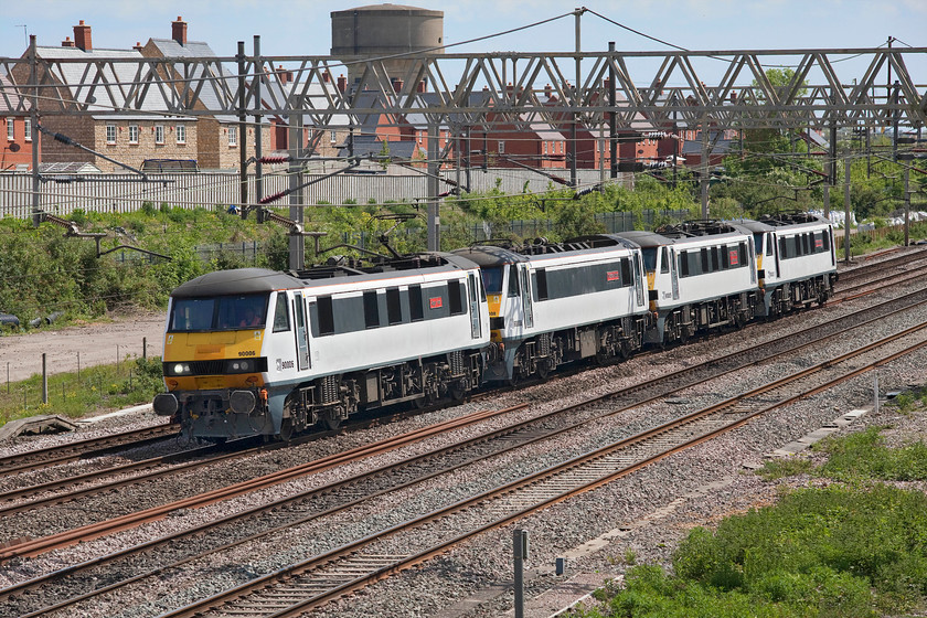 90006, 90008, 90005 & 90007, 08.42 Norwich Crown Point-Crewe Basford Hall (0Z25, 5E), site of Roade station 
 Looking more like that they have just emerged from the works rather than going to a new operator ready for a repaint into their corporate colours, a quartet of former Greater Anglia Class 90s passes the site of Roade station as the 0Z25 08.42 Norwich Crown Point to Crewe Basford Hall working. 90006 'Roger Ford', 90008 'The East Anglian', 90005 'Vice-Admiral Lord Nelson' and 90007 'Sir John Betjeman' are heading to Freightliner's headquarters at Basford Hall to enter a new phase of their working life as freight locomotives - a process that is reported to be starting by July. One wonders if they will still be wearing their nameplates when they emerge in their new green livery? 
 Keywords: 90006 90008 90005 90007 08.42 Norwich Crown Point-Crewe Basford Hall 0Z25 site of Roade station Greater Anglia GA Roger Ford The East Anglian Vice-Admiral Lord Nelson Sir John Betjeman