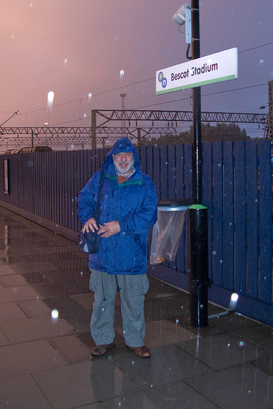 Andy, Bescot Stadium station 
 Andy and I have been trying to 'bag' Bescot Stadium station for a number years always finding ourselves passing over it on the elevated section of the M6 motorway late in the evening on our way back home never actually taking the time to detour and stop. This time we have done it even if it is in the pouring rain at six in the morning! Notice the two redundant and stored Class 08 shunters to the left just appearing above the fence. 
 Keywords: Andy Bescot Stadium station