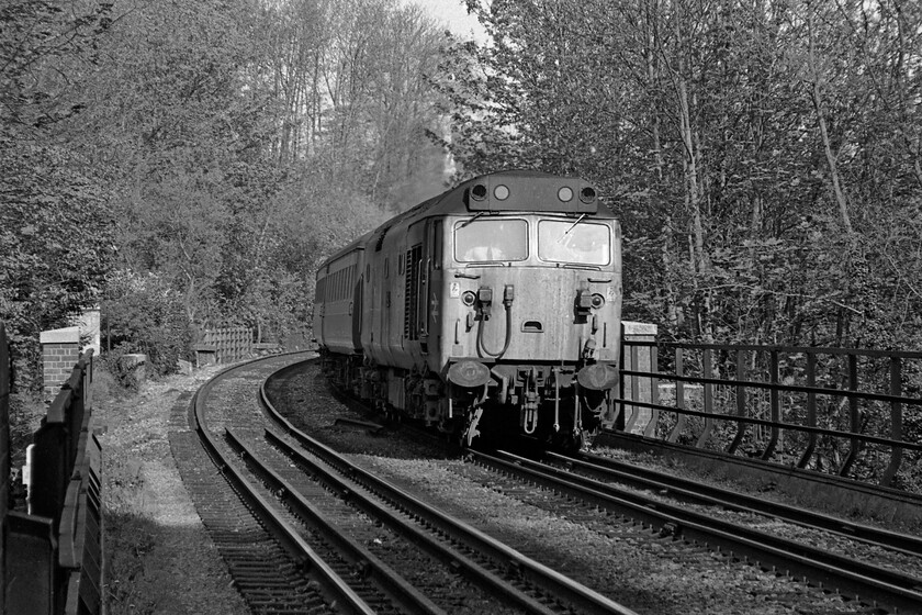 Class 50, unidentified down diverted working, Bradford-on-Avon level crossing 
 The front of a down diverted service from Paddington just catches some late afternoon sunshine before plunging into Bradford-on-Avon's relatively short seven chains long tunnel. It is crossing the River Avon, something it will do a number of times as it makes its way along the valley to Bathampton Junction where it will rejoin the GWML in seven miles time. Unfortunately, I do not have the number of the Class 50 leading the train. 
 Keywords: Class 50 diverted working Bradford-on-Avon level crossing