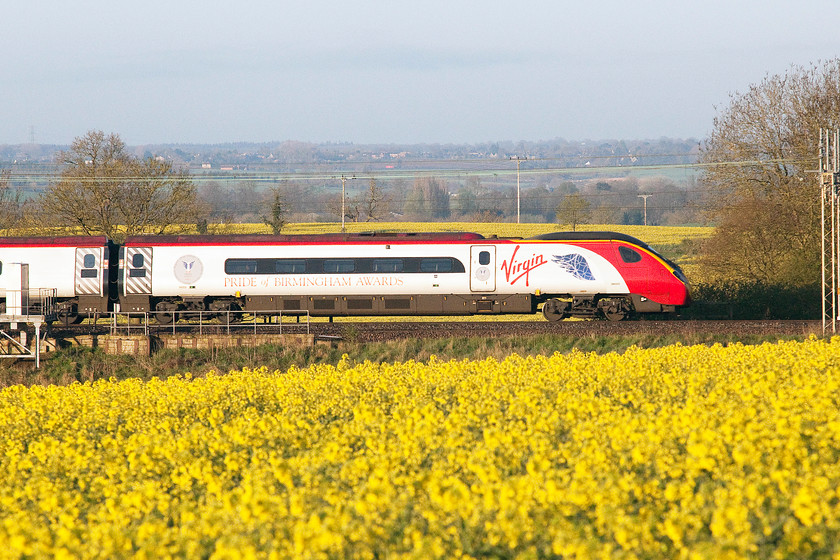 390002, VT 06.05 London Euston-Preston (1S37), between Roade & Ashton 
 Proudly wearing its Pride of Birmingham Awards vinyls 390002 'Stephen Sutton' passes through the oilseed rape fields just south of Roade in Northamptonshire with the 06.05 Euston to Preston. 
 Keywords: 390002 06.05 London Euston-Preston 1S37 between Roade & Ashton