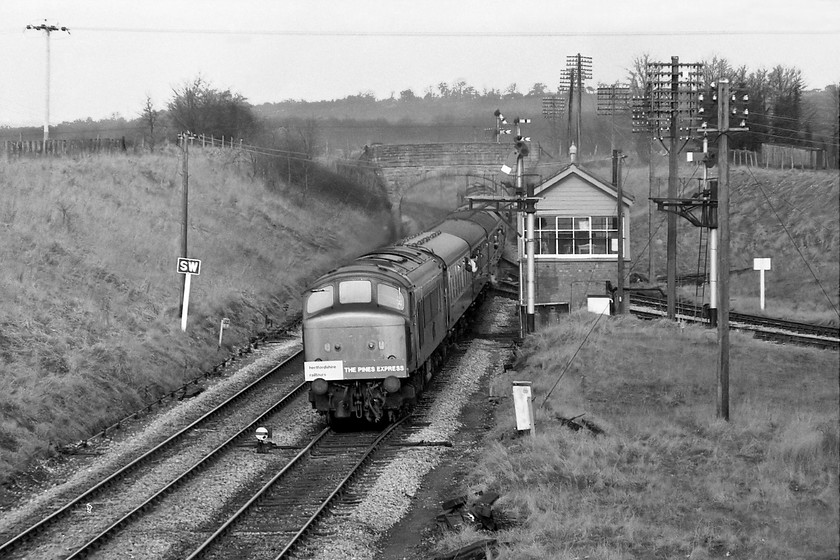 46013, outward leg of The Pines Express, 07.48 London Paddington-Weymouth (via Bristol & various freight lines), Hawkeridge Junction 
 Having been to Bristol and up the Avonmouth branch to Hallen Marsh, The Pines Express returns to Westbury and is seen passing Hawkeridge Junction. This time, the locomotive is wearing its headboard for the first time since it left Paddington due to numerous locomotive changes. Hawkeridge Junction is a perfect illustration of GWR infrastructure in this image from the cast whistle sign, the lower quadrants signals and the delightful signal box. Hawkeridge Junction was usually switched out, as it was on this day in March 1979. 
 Keywords: 46013 The Pines Express 07.48 London Paddington-Weymouth Hawkeridge Junction