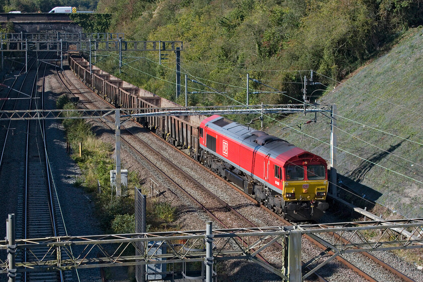 66020, 11.59 Burton-ot-Wetmore-Acton TC (6V06, 1E), former A508 bridge 
 The 11.59 Burton-ot-Wetmore to Acton empty spoil train passe Roade hauled by 66020. The balancing down working takes spoil from HS2 works around west London for disposal but should not bring any back. However, a close examination of the photograph reveals that the rear three jumbo box wagons reveals that they are still fully loaded! 
 Keywords: 66020 11.59 Burton-ot-Wetmore-Acton TC 6V06 former A508 bridge DB Cargo