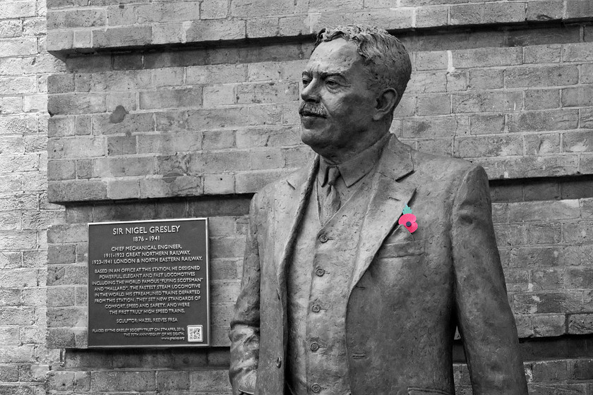 Statue, Sir Nigel Gresley, London King`s-Cross station 
 A statue of the former the former LNER CME Sir Nigel Gresley (1876-1941) stands on the new concourse at London King's Cross. The plaque to the left provides information about him to any passing passengers who care to pause for a moment. I have manipulated this image a little by desaturating it but at the same time leaving the remembrance poppy that has been placed on his lapel to shine through in its original colour. 
 Keywords: Statue Sir Nigel Gresley London King`s-Cross station