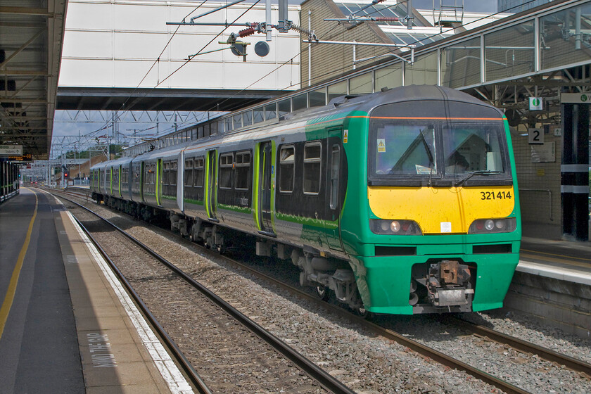 321414, LM 11.47 Milton Keynes Central-London Euston (2K26), Milton Keynes Central station 
 321414 is one of a small number of 'dusty bins' that have been retained by London Midland that have been repainted into their corporate colours. They are used to supplement peak-time services and to work 'local' stopper services between Milton Keynes and Euston. At Milton Keynes, the 11.47 service waits to depart for the capital running as 2K26. This train will stop at virtually every station between the two places and will thus take considerably over an hour and a half, a distance covered by a Virgin service in twenty-five minutes! 
 Keywords: 321414 11.47 Milton Keynes Central-London Euston 2K26 Milton Keynes Central station London Midland