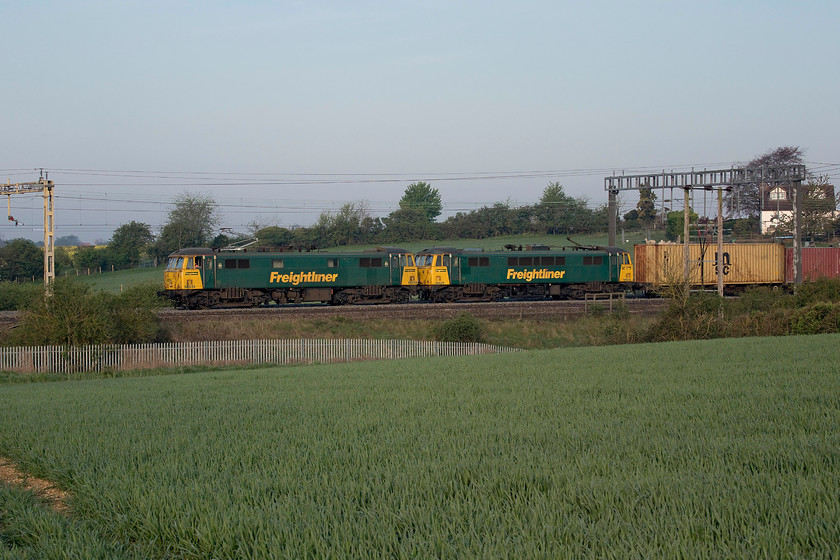 86639 & 86637, 21.25 Coatbridge-Felixstowe North (4L89, 1L), between Roade & Ashton 
 No panning of the camera or a ridiculously fast shutter speed needed here as the overnight 4L99 Coatbridge to Felixstowe Freightliner was at a walking pace approaching a red signal on the up fast line between the villages of Roade and Ashton. The adverse signal was because the 4L52 that was just in front of it had also slowed for the approach to Hanslope Junction to cross from the fast to the slow leaving 86639 and 86637 to continue fast beyond Milton Keynes and, in doing so, thus overtaking the preceding working. The sun is struggling to break through the slightly hazy sky at this stage that has just taken the edge off the lighting. 
 Keywords: 86639 86637 21.25 Coatbridge-Felixstowe North 4L89 between Roade & Ashton Freightliner