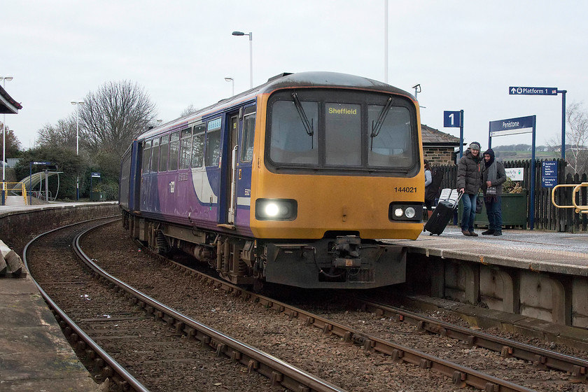 144021, NT 15.12 Huddersfield-Sheffield (2B21, RT), Penstone station 
 144021 waits at Penistone station with the 15.12 Huddersfield to Sheffield. Notice the ancient track still in use complete with check rails due to the sharp curve. As the class 144 have no bogies running on fixed axles and with them having a long wheel-base leads to ear piercing flange squeal and this was particularly bad as the train passed us at the flat foot crossing where we were standing. 
 Keywords: 144021 15.12 Huddersfield-Sheffield 2B21 Penstone station