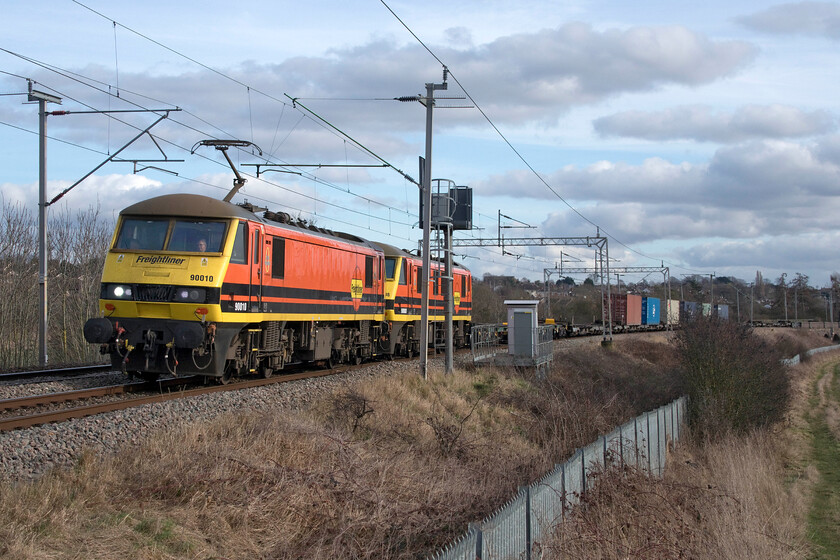 90010 & 90008, 09.12 Felixstowe North-Trafford Park (4M63, RT), Wilson's crossing 
 I am of the firm opinion that the corporate Genesee & Wyoming livery applied to Freightliner operated Class 90s is absolutely superb! Passing Kingsthorpe to the north of Northampton 90010 leads 90008 working the 4M63 09.12 Felixstowe to Trafford Park service. The boxes visible on the train are all that was being carried bare two mini boxes at the rear a ridiculously easy load for the combined ten thousand horsepower available! Interestingly, I have a photograph of the same two Class 90s in a different working phase of their life at Norwich, see..... https://www.ontheupfast.com/p/21936chg/29952518804/x90008-11-30-norwich-london-liverpool 
 Keywords: 90010 90008 09.12 Felixstowe North-Trafford Park 4M63 Wilson's crossing Freightliner