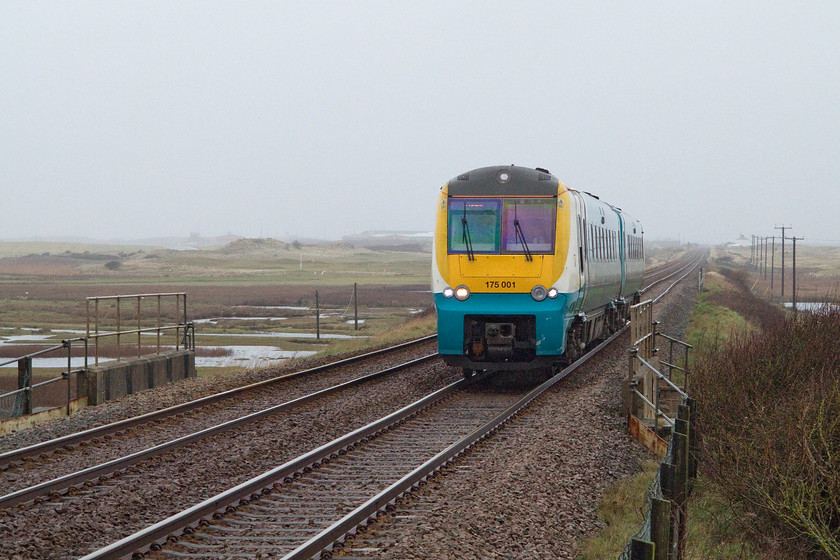 175001, AW 10.40 Holyhead-Llanelli (1V95), Rhosneiger station 
 ATW's 170001 approaches Rhosneiger station working the 10.40 Holyhead to Llanelli service. Across the dunes through the murk in the distance is RAF Valley. This is the base used for RAF search and rescue training. It is also the location for Anglesey's new purpose built airport (Maes Awyr Mn) that was opened to great fanfare in 2007. 
 Keywords: 175001 10.40 Holyhead-Llanelli 1V95 station