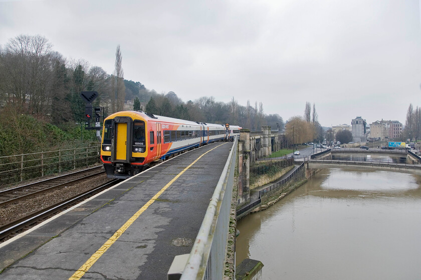 159105, SW 12.51 Bristol Temple Meads-London Waterloo, Bath Spa station 
 Using a relatively wide angle setting on the lens has enabled this photograph at the west end of Bath Spa station to include the rather brown-looking River Avon that also flows under this part of the station. Brightening up a rather drab February scene SWT's 159105 arrives with the 12.51 Bristol to Weymouth service. 
 Keywords: 159105 12.51 Bristol Temple Meads-London Waterloo Bath Spa station South West Trains