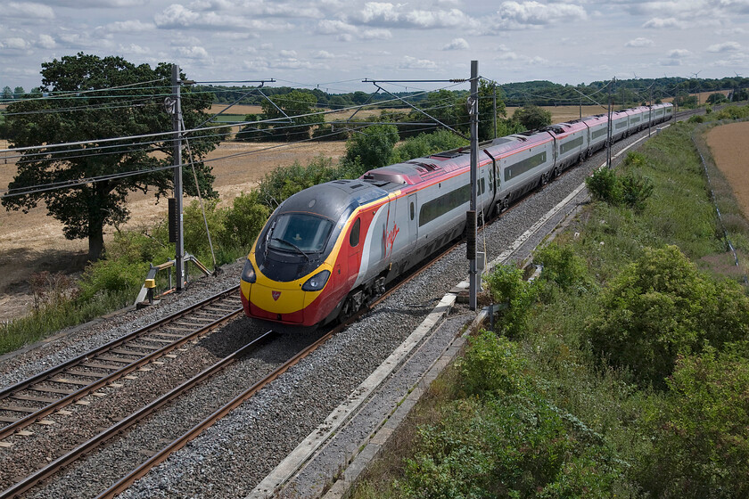 390047, VT 10.50 London Euston-Wolverhampton (1G06), Blisworth 
 Virgin's 390047 works the 10.50 Euston to Wolverhampton service near the village of Blisworth in Northamptonshire. After a morning of brilliant sunshine the cloud has begun to gather but the temperature remains hot making for a stormy end to this particular Sunday. 
 Keywords: 390047 10.50 London Euston-Wolverhampton 1G06 Blisworth Virgin Pendolino