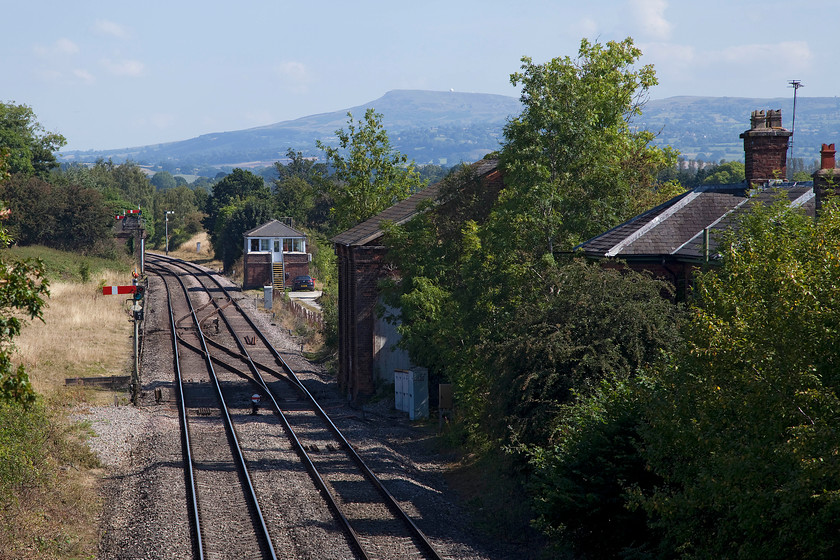 Woofferton Junction signal box (LNW & GW Joint, c.1875) & former Woofferton station 
 Looking from the south Woofferton's old station buildings can be seen in the trees to the right. Beyond that, in the distance, is the 1875 LNW & GW Joint signal box and its associated signalling. In the background is the well known landmark of Clee Hill with the larger 'golf ball' at the top that forms part of the NATS radar network that keeps our aeroplanes flying safely in the sky. 
 Keywords: Woofferton Junction signal box Woofferton station