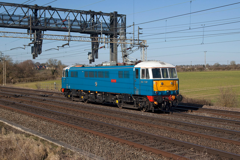 86259, 12.40 Acton CS-Rugby CS LE (0Z88), Roade Hill 
 I don't take many going-away shots, but when the lighting is right and if it's a light engine it doesn't really matter does it? Here at Roade Hill on the southern WCML, 86259 'Les Ross/Peter Pan' returns from Acton to its home in Rugby carriage sidings following hauling the of the Cumbrian Mountains Express the previous day. Despite the blue skies and sunshine, I was very relived to be able to pack up and go home as the wind was bitter at this exposed location. 
 Keywords: 86259 Les Ross Peter Pann 12.40 Acton CS-Rugby CS 0Z88 Roade Hill