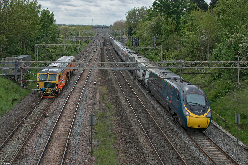 DR73929, ballasting & 390153, VT 10.19 London Euston-Manchester Piccadilly (1H05, 15L), Victoria bridge 
 Colas 08-4x4/4S-RT switch and crossing tamper DR73929 does its work near Victoria bridge (just south of Roade) whilst the adjacent fast lines remain open. One of the operators of the tamper is seen climbing down from the front cab to observe its operation as it passes by very close to one of two concrete culvert covers both previously marked with a white stripe of paint. The Avanti West Coast train is the 10.19 Euston to Manchester service worked by 390153. 
 Keywords: DR73929 390153 10.19 London Euston-Manchester Piccadilly 1H05 Victoria bridge Avanti West Coast Pendolino