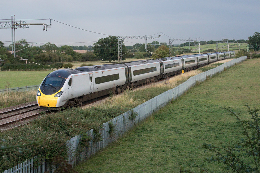 390005, VT 18.55 London Euston-Manchester Piccadilly (1H04, 6L), Wright's Lane bridge 
 The yellow milepost in the middle distance puts this location, Wright's Lane bridge, between Gayton and Rothersthorpe at sixty-four miles from Euston. 390005 'City of Wolverhampton' has taken just about forty minutes to reach this location working the 18.55 Euston to Manchester Piccadilly Avanti West Coast 1H04 service. The sun has just managed to get through the cloud that enveloped the sky on this extremely hot day turning it into a humid evening and night. 
 Keywords: 390005 18.55 London Euston-Manchester Piccadilly 1H04 Wright's Lane bridge Avanti West Coast Pendolino City of Wolverhampton