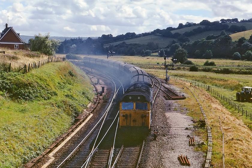 50040, 12.20 Penzance-London Paddington, Cowley Bridge junction 
 As the farmer in the adjacent field attempts to 'make hay while the sun shines' 50040 'Centurion' is seen approaching Cowley Bridge Junction with the 12.20 Penzance to London Paddington getting up to speed after its stop at Exeter St. David's. Cowley Bridge is the point where the present day Tarka Line diverges off towards Barnstable. In the past, it was a much busier junction as the former LSWR line also diverged here as it continued west being an alternative and, some say, a better route to the rest of Devon and Cornwall. This image clearly illustrates the shocking state that the class 50s had been allowed to get in prior to their extensive overhaul at Doncaster Works. Not only is 50040 in poor external condition but it is smoking badly as it gets up to speed. 
 Keywords: 50040 12.20 Penzance-London Paddington Cowley Bridge junction