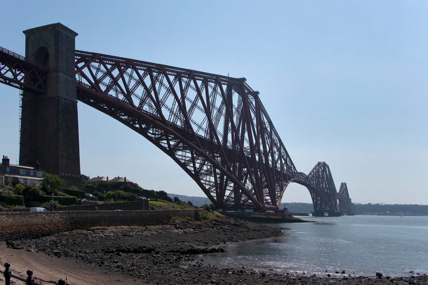 The Forth Bridge, North Queensferry 
 Andy and I parked the car in the small car park just visible in front of the two bungalows at North Queensferry. Parked right underneath the Forth Bridge by the stone pier made you realise just how huge the structure is....it's gargantuan! We then sat and had a break in a nearby caf and both commented on the number of trains rattling over the bridge in the relatively short time it took to have a pot of tea. I suppose if you lived in one of the said houses in this image, like everything you would get used to the noise! 
 Keywords: The Forth Bridge North Queensferry