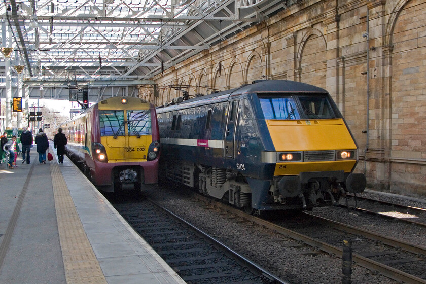 334032, 13.48 Edinburgh Waverley-Helensburgh Central & 91124, GR, 09.30 London King's Cross-Edinburgh Waverley, Edinburgh Waverley station 
 Two trains display two defunct liveries at Edinburgh Waverley station! To the left 334032 will work the 13.48 service to Helensburgh Central still wearing its Strathclyde Partnership for Transport livery that is in the process of being replaced by a much more modern and up-to-date SctoRail Soltare paint scheme. To the right, 91124 arrives in the Scottish capital with the 09.30 from King's Cross. This locomotive is branded 'East Coast' but still wears its GNER paint which it has done so since 1997. 
 Keywords: 334032 13.48 Edinburgh Waverley-Helensburgh Central 91124 09.30 London King's Cross-Edinburgh Waverley Edinburgh Waverley station Scotrail East Coast IC225 Strathclyde Partnership for Transport)