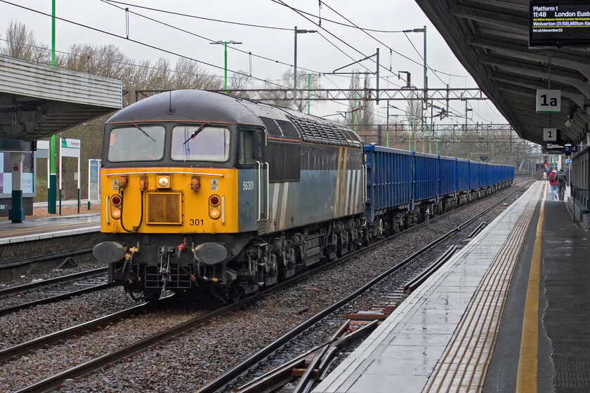 56301, 07.44 Chaddesden Sidings-Wembley Reception Sidings (4Z43, 8E), Northampton station 
 Grid 56301 passes through Northampton's centre road leading the 07.44 Chaddesden to Wembley stone train, a move in association with HS2. As 56045 this Doncaster-built example entered service in the summer of 1978 and is seen here still wearing its now-defunct Fastline livery. It is a mainline registered preserved member of the class owned by the Class 56 Group on hire to spot hire company BARS (British American Railway Services). So as a forty-five-year-old locomotive heads south an even older one was approaching me from behind...... 
 Keywords: 56301 07.44 Chaddesden Sidings-Wembley Reception Sidings 4Z43 Northampton station Grid