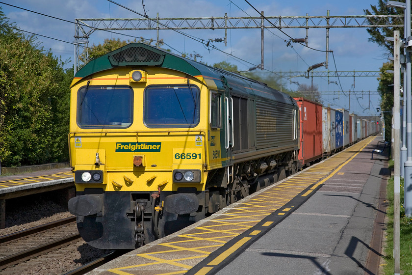 66591, 13.30 Felixstowe North-Lawley Street (4M93), Hatfield Peverel station 
 66591 passes Hatfield Peverel station at, what I would have estimated to be, its maximum sixty miles per hour; it certainly left quite a draft in it wake felt while standing on the station's relatively narrow platform. The Freightliner 66 was hauling the 4M93 13.30 Felixstowe to Hams Hall (Birmingham) service that was just a short distance into its journey. Apart from the first and the last few miles, this journey is entirely under the wires but despite this, a diesel (usually a Class 70) is still thought to be the best form of haulage. Maybe some more creative thinking is required to enable its to be electrically hauled? 
 Keywords: 66591 13.30 Felixstowe North-Lawley Street Hatfield Peverel station 4M93 Freightliner