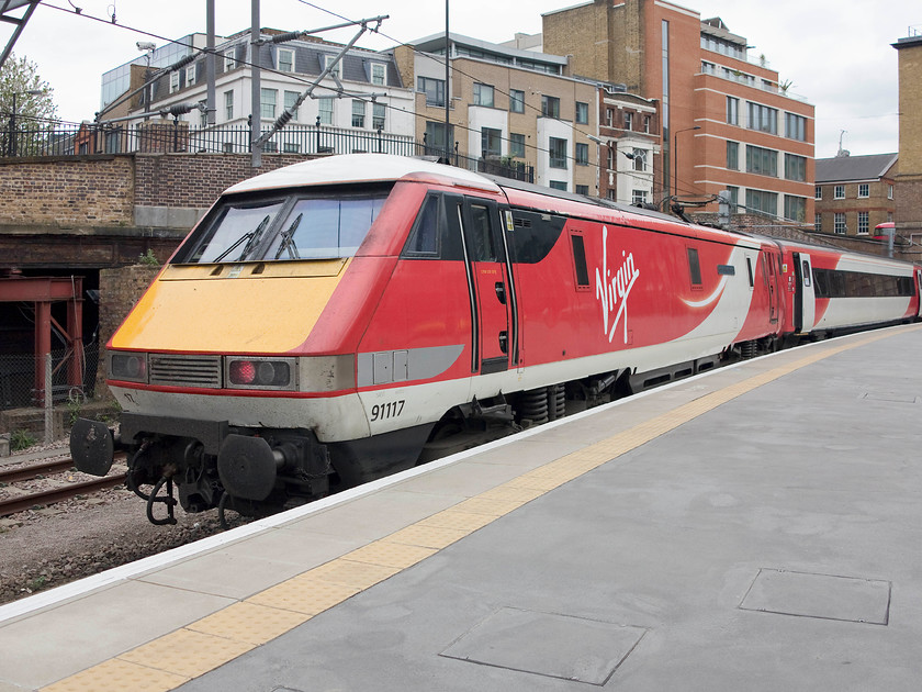 91117, GR 16.15 London Kings Cross-Ferme Park ECS (5Y33), London Kings Cross station 
 Having recently arrived with a service from the north, 91117 'West Riding Limited' has a brief rest before a driver will join the train and work the 16.15 to Ferme Park, an ECS move for the train to be stabled and serviced. Just in the background to the left is the entrance to the tunnel that took the Metropolitan line extension down into the depths to Moorgate station. The platform, just by the tunnel entrance, was referred to as King's Cross York Road and was only served by northbound trains. Services ceased in 1977 but I recall 31s hauling rakes of suburban stock out of the tunnel and into the daylight at this spot in my early spotting days. 
 Keywords: 91117 ECS 5Y33 London Kings Cross station