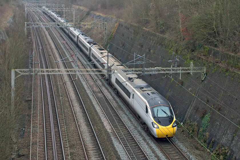 Class 390, VT 12.23 London Euston-Birmingham New Street (9G20, RT), Roade cutting 
 Another 'nude' Pendolino passes through Roade cutting. Avanti West Coast is making very slow progress with its re-branding of their stock with the majority running in this plain white livery. This unidentified member of the class is working the 12.23 Euston to Birmingham New Street. 
 Keywords: Class 390 12.23 London Euston-Birmingham New Street 9G20 Roade cutting Pendolino Avanti West Coast